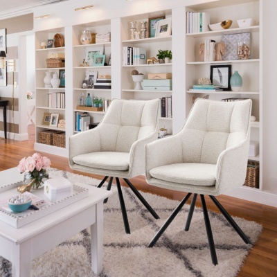 Duas cadeiras brancas de tecido com estrutura preta em sala com estantes e decoração