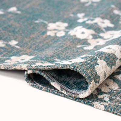 Tapete azul esverdeado com padrão floral branco dobrado sobre fundo branco