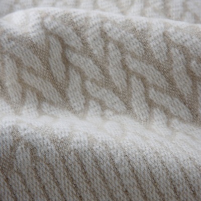 Tecido de tricô bege e branco com padrão entrelaçado