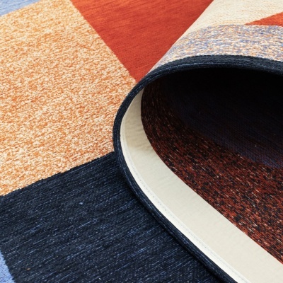 Tapete colorido geométrico enrolado sobre piso de madeira