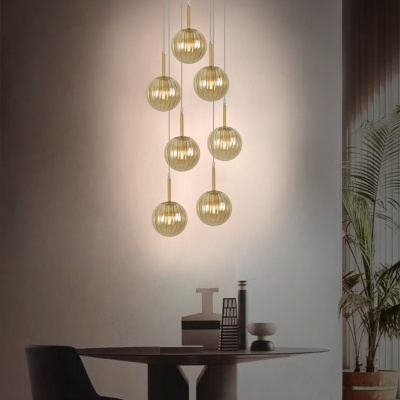 Lustres pendentes esféricos em vidro dourado sobre mesa preta com cadeira e vasos décor