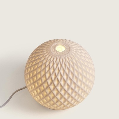 Luminária esférica branca com padrão geométrico e luz amarela