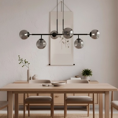 Sala de jantar minimalista com mesa de madeira clara, seis cadeiras estofadas creme e candeeiro suspenso com globos de vidro fumado.