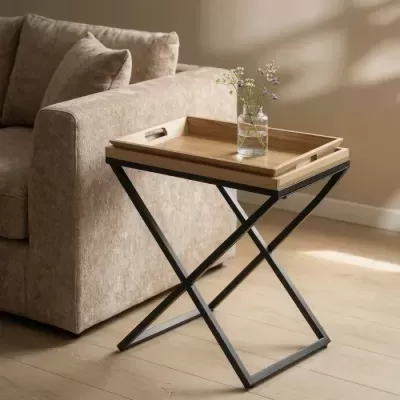 Mesa auxiliar com tampo de madeira e base metálica preta ao lado de sofá bege
