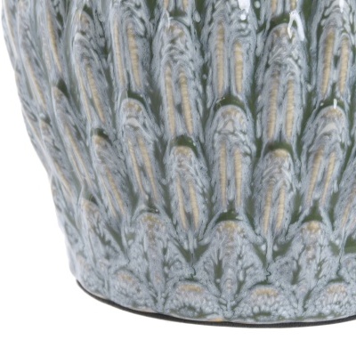 Pormenor circular de vaso cerâmico verde com padrão texturizado e verniz brilhante