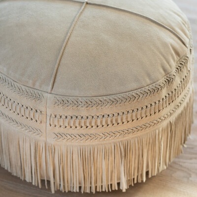 Pufe bege de camurça com franjas em chão de madeira clara