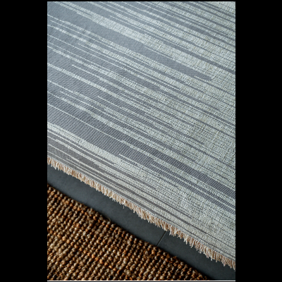 Toalha de mesa cinza com padrão de linhas brancas e franjas na borda