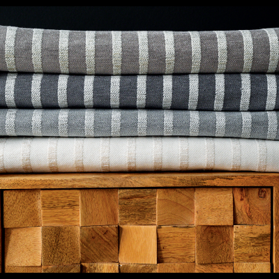 Três mantas dobradas com padrão de riscas e franjas, sobre móvel de madeira