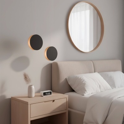 Quarto com cama e mesa de cabeceira em madeira clara com relógio digital e vaso, espelho redondo e luzes suspensas.
