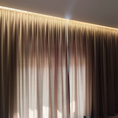 Cortinas bege opacas iluminadas por luz amarela no teto