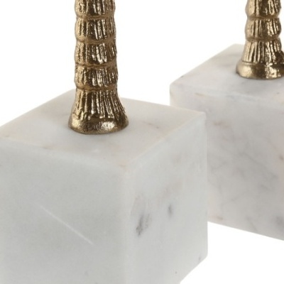 Cubos de mármore branco com estruturas metálicas douradas texturadas no topo