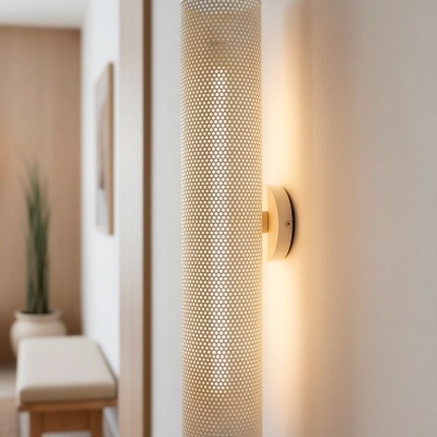 Aplica de parede cilíndrica branca perfurada com luz quente numa sala moderna