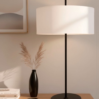 Candeeiro de mesa preto com cúpula branca junto a vaso preto e livros sobre móvel de madeira