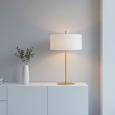 Candeeiro de mesa dourado com cúpula branca num móvel branco minimalista com vaso branco e folhas verdes