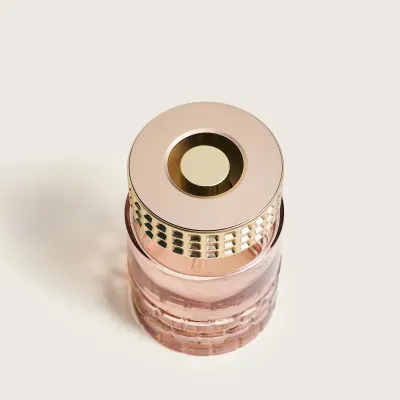 Frasco de vidro rosa com tampa dourada para perfume