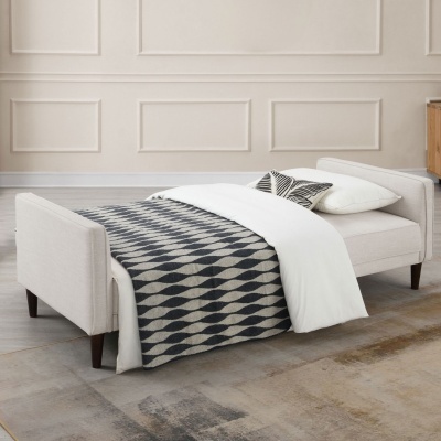 Sofá-cama bege com manta geométrica e almofadas em ambiente neutro