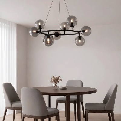 Mesa de jantar redonda em madeira escura com quatro cadeiras cinza e candeeiro de teto moderno com globos de vidro fumê.