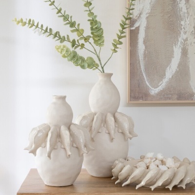 Vasos cerâmicos brancos decorativos sobre móvel de madeira clara com textura de vime