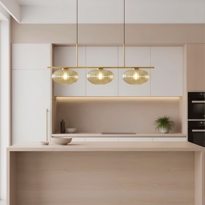 Cozinha moderna com ilha em madeira clara e luminária suspensa dourada com três abajures ovalados