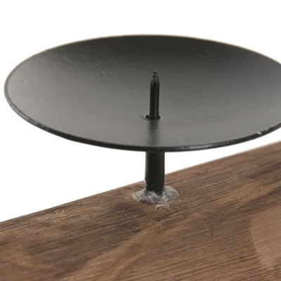 Suporte de castiçal em metal preto sobre base de madeira.