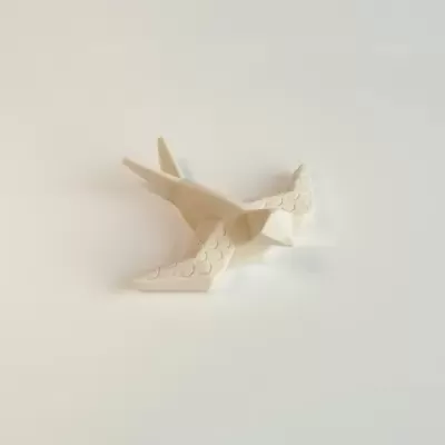 Ar de cerâmica branca em forma de pássaro com textura de penas