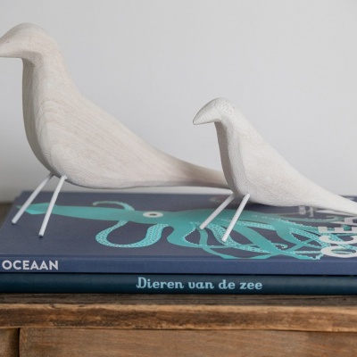 Dois pássaros decorativos de madeira sobre livros sobre mesa de madeira.