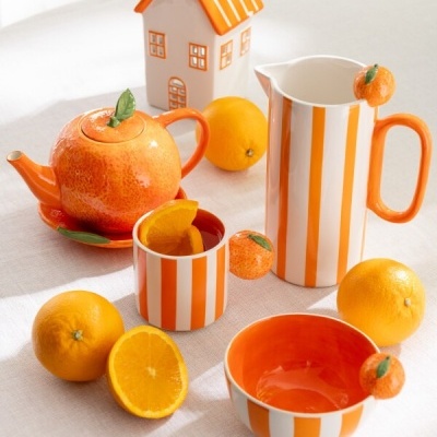 Conjunto de porcelana laranja e branco com várias laranjas naturais e casa decorativa.