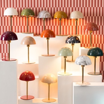 Candeeiros de mesa coloridos com base dourada expostos em blocos brancos