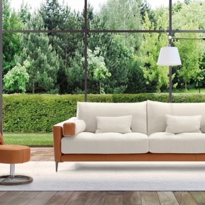 Sala com sofá branco e castanho, poltrona castanha reclinável, candeeiro e vistas para jardim verde