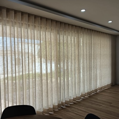 Cortinas bege claro texturizadas numa sala com janela panorâmica e chão em madeira