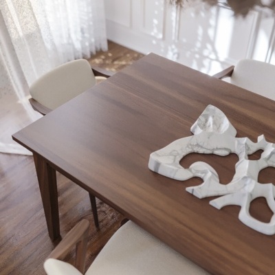 Mesa de jantar em madeira com cadeiras estofadas creme e decoração em mármore