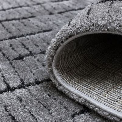 Tapete cinzento com padrão geométrico felpudo e textura textil na base