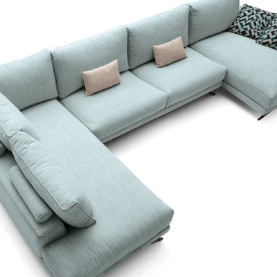 Sofá em U estofado azul claro com almofadas bege e geométricas