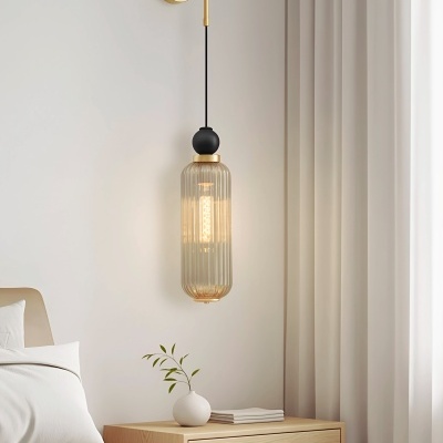 Luminária suspensa de vidro canelado dourada e preta junto a mesa de cabeceira de madeira clara