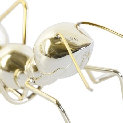 Escultura metálica de formiga dourada e prata em fundo branco