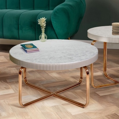 Mesa de centro redonda em mármore branco com base dourada e vaso com plantas ao lado de sofá verde