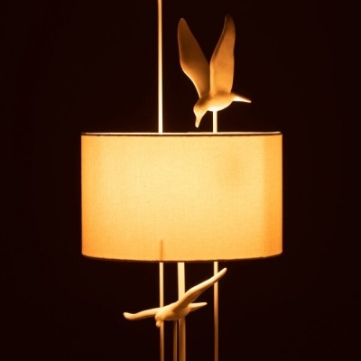 Candeeiro de mesa com abajur bege e aves decorativas brancas.