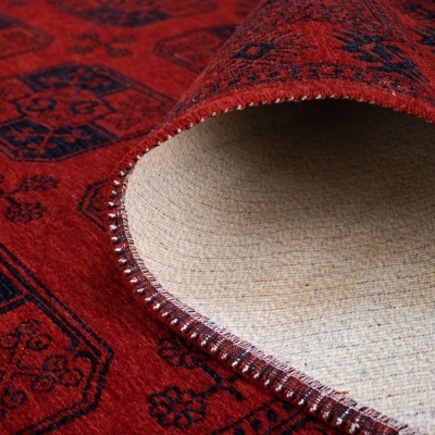 Tapete vermelho com padrões geométricos azuis e rebordo costurado, parte inferior em tecido cru.