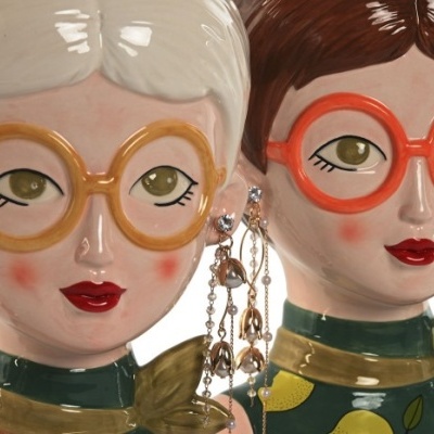 Duas esculturas cerâmicas femininas com óculos grandes e coloridos
