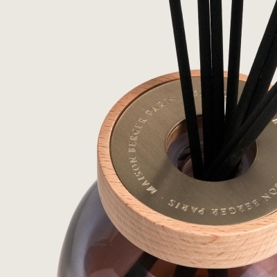 Difusor de fragrância em vidro castanho com tampa em madeira e metálica, varetas pretas.