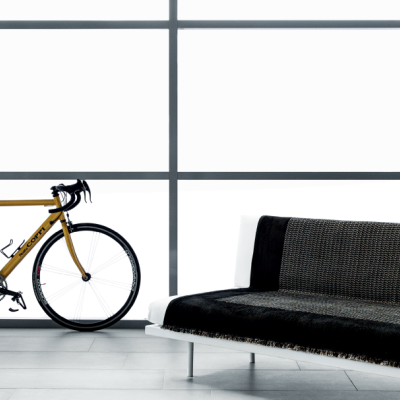 Bicicleta de estrada amarela ao lado de sofá preto num interior claro