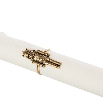 Anel dourado com design de canhão à volta de guardanapo branco