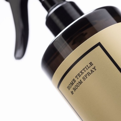 Frasco spray preto com rótulo amarelo com texto