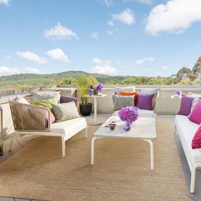 Conjunto de mobiliário de exterior com sofás brancos, almofadas coloridas e mesa branca com flores