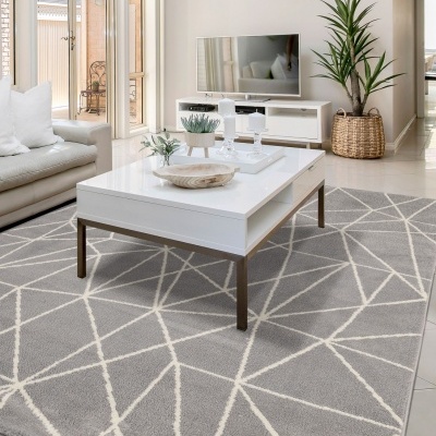 Mesa de centro branca sobre tapete cinzento geométrico em sala moderna