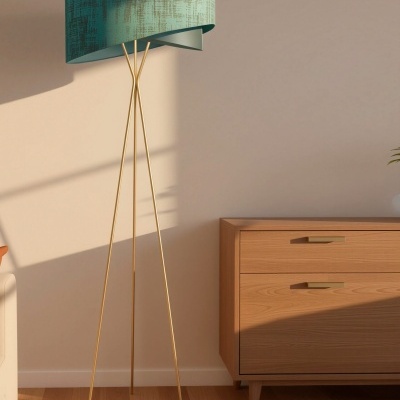 Candeeiro de pé com cúpula azul e base metálica dourada ao lado de cómoda de madeira clara