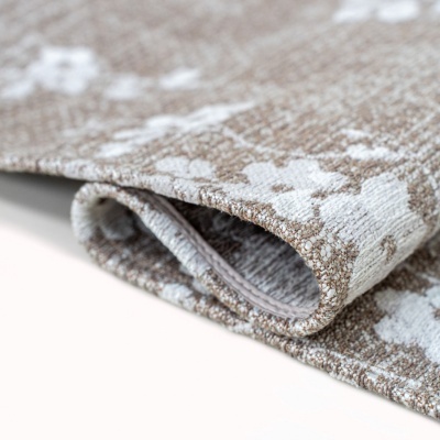 tapete tecido castanho claro com flores brancas dobrado