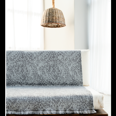 Sofá de madeira com manta cinza e lâmpada de vime suspensa