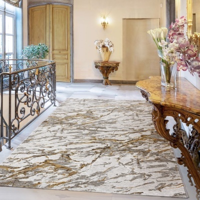 Tapete abstrato cinza, bege e dourado numa sala com chão de pedra e móveis de madeira entalhada