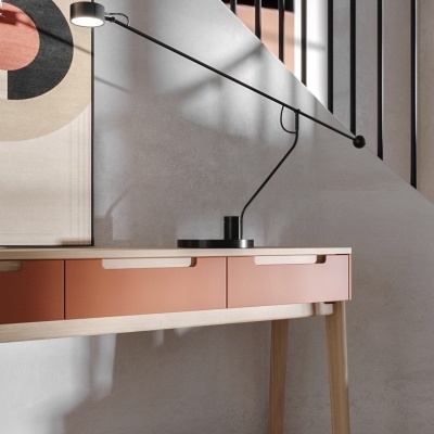 Candeeiro de secretária preto sobre mesa com gavetas terracota e parede cinza